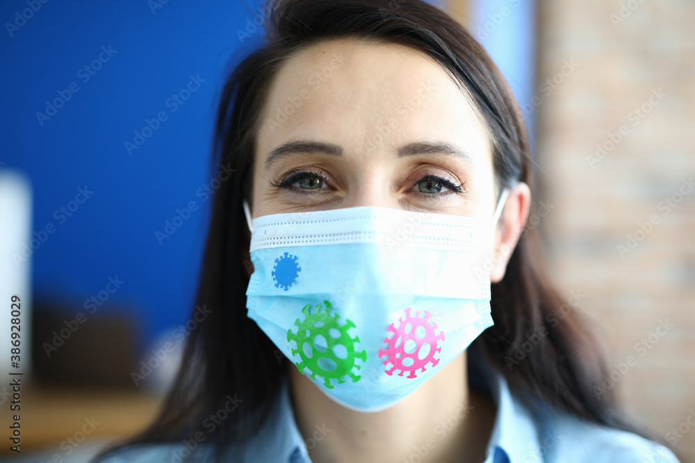 Portrait of woman in protective medical mask with stickers of bacteria. Health safety in pandemic concept