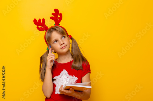Little girl thinking while writing a letter to Santa