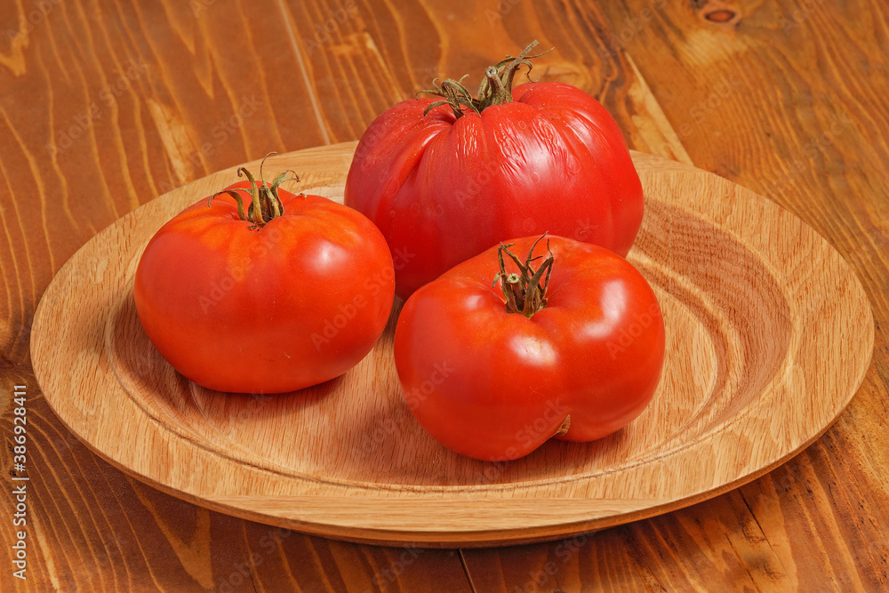 Tomatoes lie on a wooden plate close up Tomatoes lie on a wooden plate close up