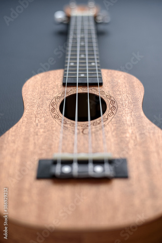 Brown ukulele on black background with shallow depht of field