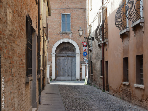 Fototapeta Naklejka Na Ścianę i Meble -  Ferrara, Italy. Cobbled street in the old town. There is an old house with a large wooden door.