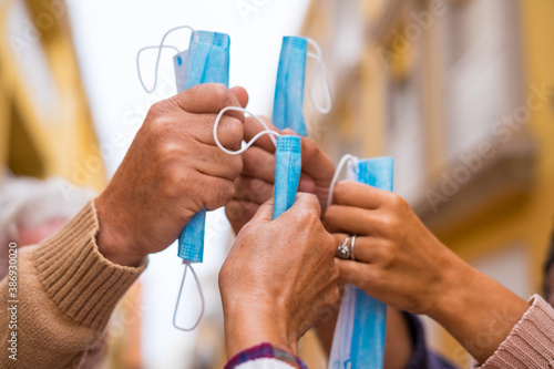 close up of a group of four hands together holding a medical and surgical mask after winnig covid-19 and be free and can no wear mask in the street photo