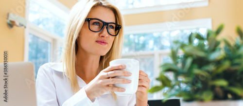 Happy young woman drinking coffee in an office