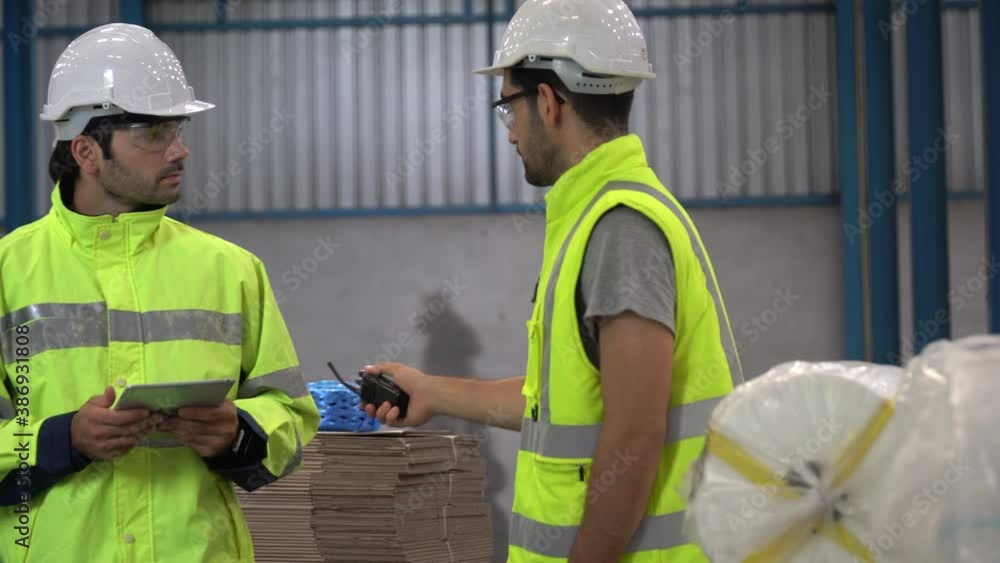 warehouse manager holding walkie talkie walking with warker man using tablet computer checking list and inventory in warehouse warehouse manager holding walkie talkie walking with warker man using tablet computer checking list and inventory in warehouse