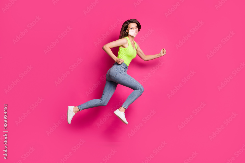 Full body profile side photo of positive girl jump run fists wearing orange face mask isolated over pink color background