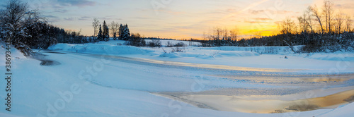 Tranquil winter landscape with ice bound river at sunrise