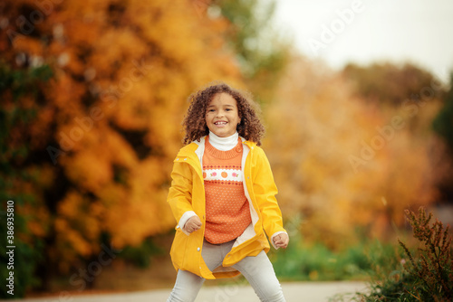 Fototapeta Naklejka Na Ścianę i Meble -  Cute afro girl smiling broadly outdoors and enjoying autumn day in park.