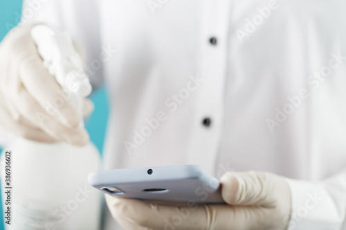 A man in Gloves handles the phone with a spray from a disinfectant