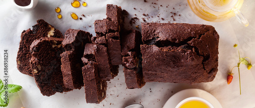 Fotografie banner of chocolate loaf cake with walnuts and prunes on the table with green tea