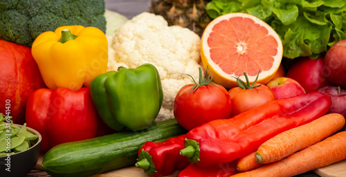 Group vegetables and Fruits Apples, grapes, oranges, and bananas in the wooden basket with carrots, tomatoes, guava, chili, eggplant, and salad on the table.Healthy food concept