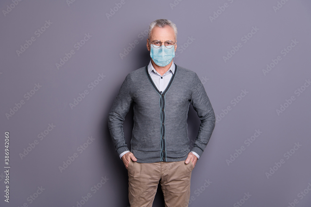 Portrait of content man wearing mask casual formal-wear holding hands in pockets isolated over gray pastel background Portrait of content man wearing mask casual formal-wear holding hands in pockets isolated over gray pastel background