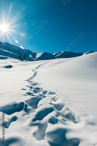 Footprints in the fresh snow mountains scenery. Beautiful winter sunrise. Adventure and travel time