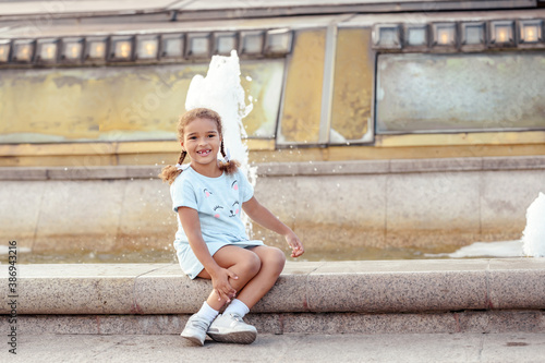 Russia, Moscow, 2019 August 31 -Portrait of a lovely little girl in the city over fountain.