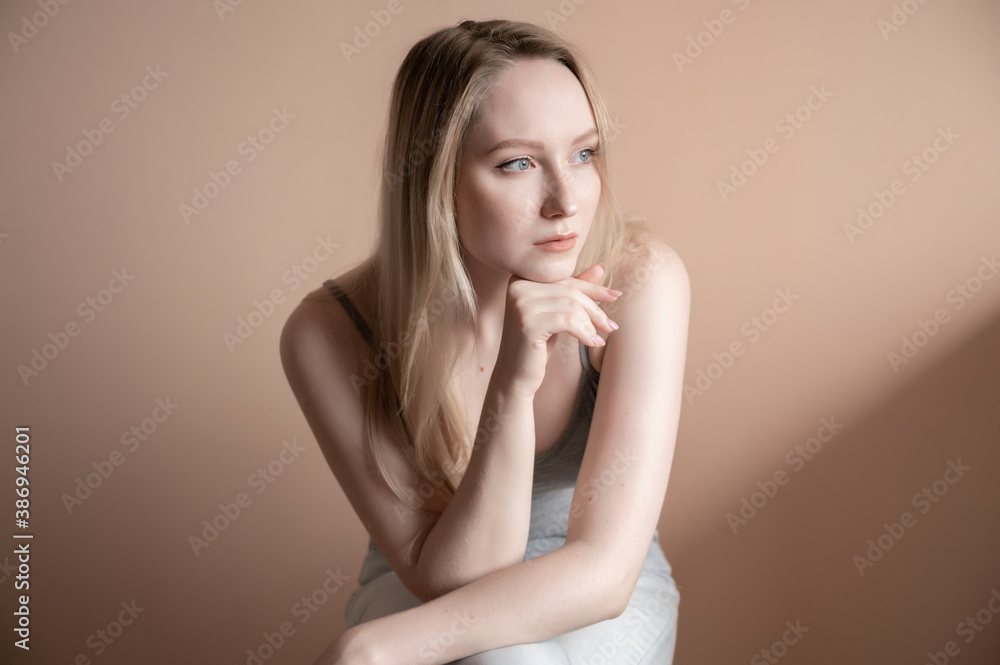 Graceful young woman posing against beige wall. Graceful young woman posing against beige wall.