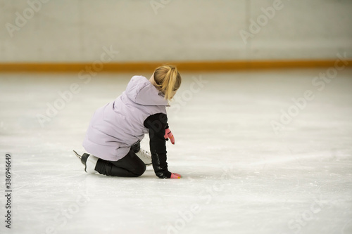 Kid fall on the ice rink. Figure skating school. Young figure skaters practicing at indoor skating rink. Kid learning to ice skate.