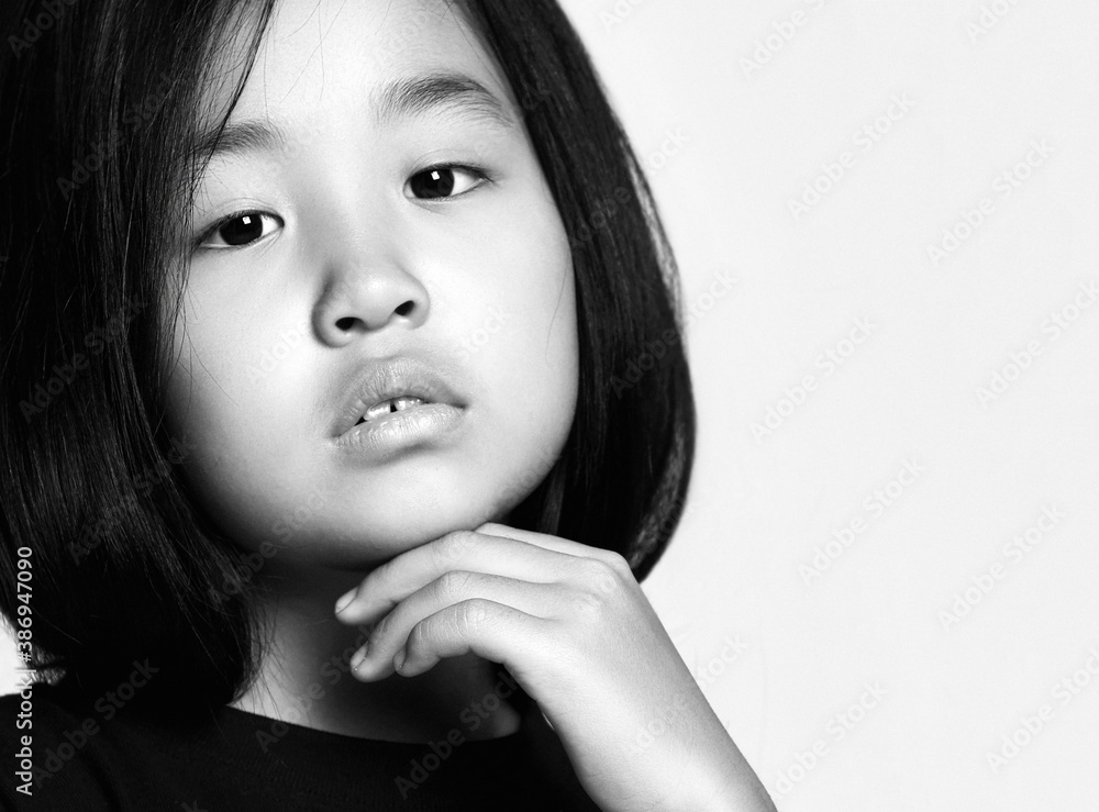 Black and white portrait of asian Korean kid girl looking at camera with her head tilted and holding hand at chin Black and white portrait of asian Korean kid girl looking at camera with her head tilted and holding hand at chin