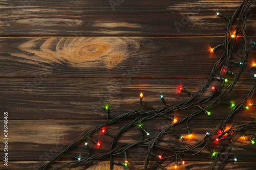 Christmas garland lights on brown wooden background.