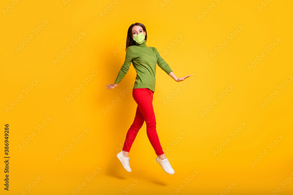 Full size profile photo of funny lady jump up walking wear mask green pullover sneakers trousers isolated yellow color background
