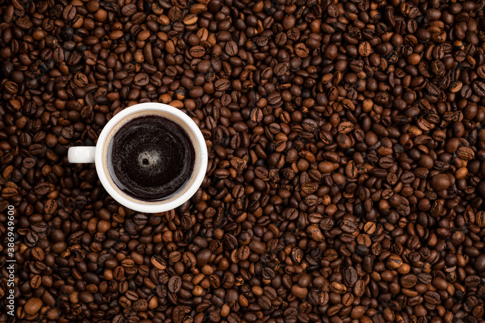 cup full of black coffee over a background of coffee beans cup full of black coffee over a background of coffee beans
