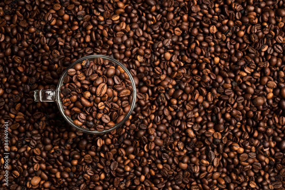 glass cup full of coffee beans over a background of coffee beans