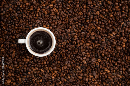 cup full of black coffee over a background of coffee beans