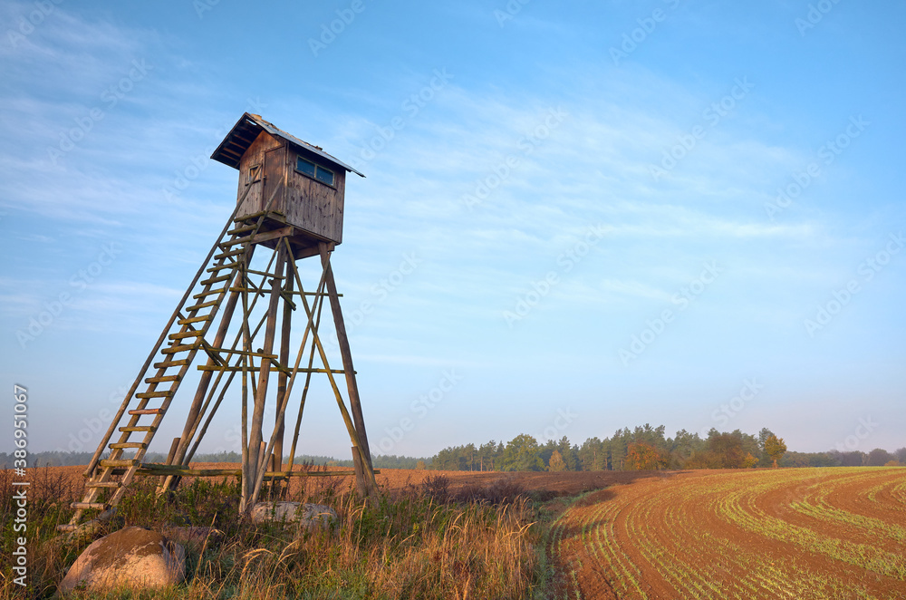 Elevated wooden hunting blind on a field in early morning.