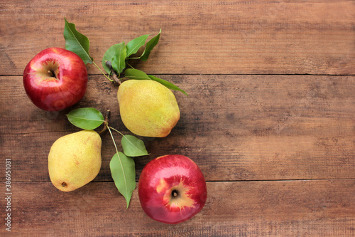 Natural red apples and yellow pears with leaves on old wooden table. Wooden background with fresh organic fruits. Autumn harvest. Flat lay. Rustic style