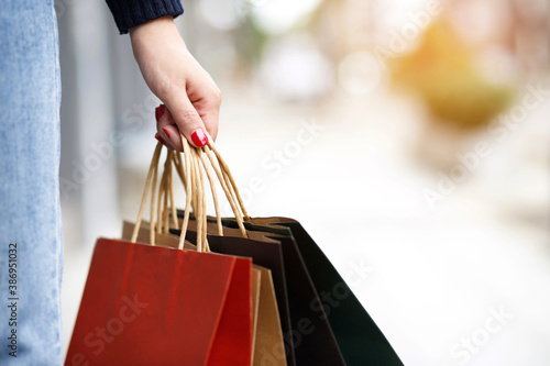 Closeup of woman hand holding shopping bag colorful paper on the street happy summer with copy space. 