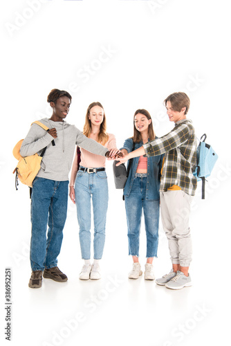 Smiling multicultural teenagers holding hands on white background