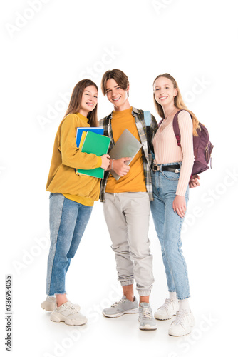 Smiling teenagers with backpacks and notebooks looking at camera on white background