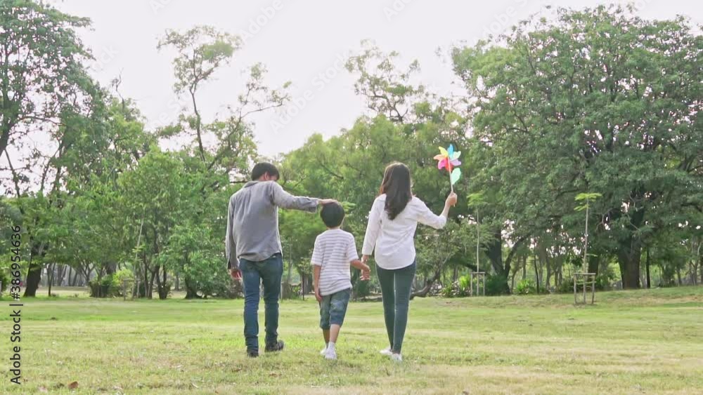 Back view of Asian family holding hand and walking together at park Back view of Asian family holding hand and walking together at park