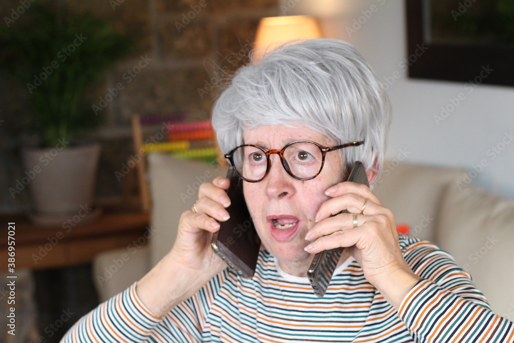 Senior overwhelmed woman using two cellphones Senior overwhelmed woman using two cellphones