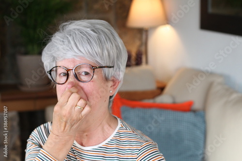 Senior woman blocking nose from unpleasant smell