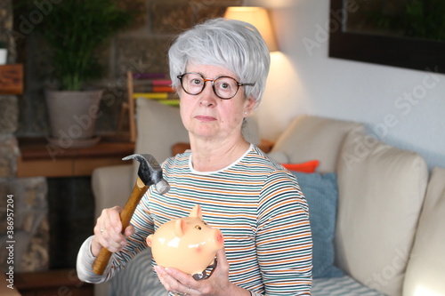 Fotografía Senior woman about to break piggy bank