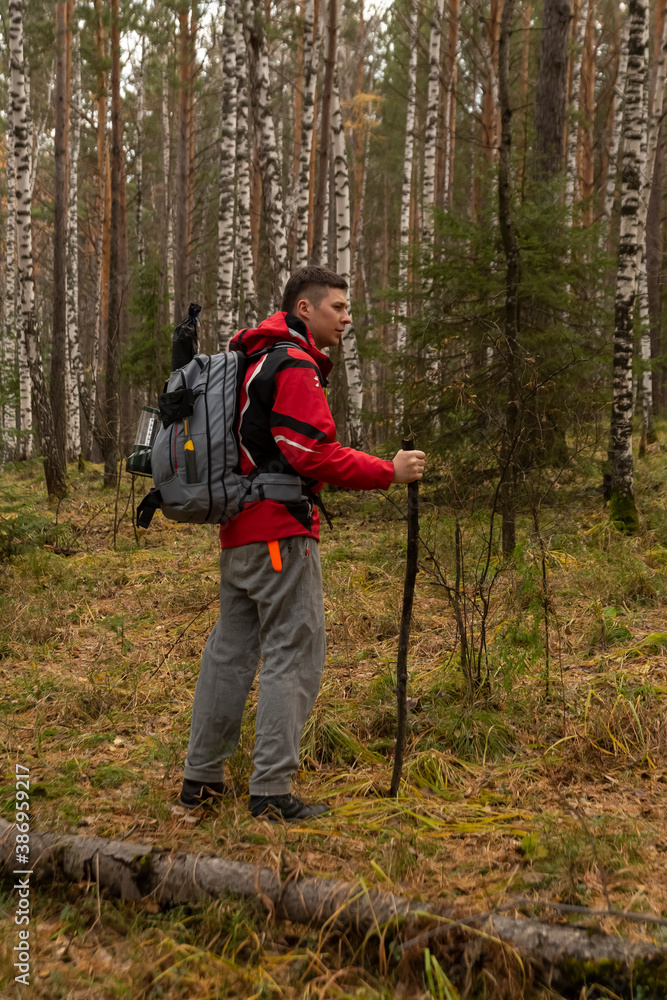 Young man in hiking clothes with a backpack, a hatchet and a lantern in the autumn forest. Tourism, activity, lifestyle. Young man in hiking clothes with a backpack, a hatchet and a lantern in the autumn forest. Tourism, activity, lifestyle.