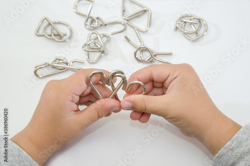 metal puzzle in hands. White background. Close-up. Concept to solve the puzzle. photo