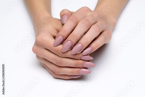Nude, beige gel extended manicure on sharp long nails close-up on a white background photo