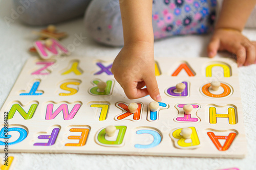 Preparing for school. Education for the youngest. Preschool education in kindergartens. little kid makes puzzles out of alphabet on floor at home.Color English Alphabet for children. puzzles on board