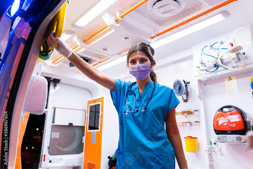 Portrait of young female paramedic with face mask working in an ambulance during pandemic