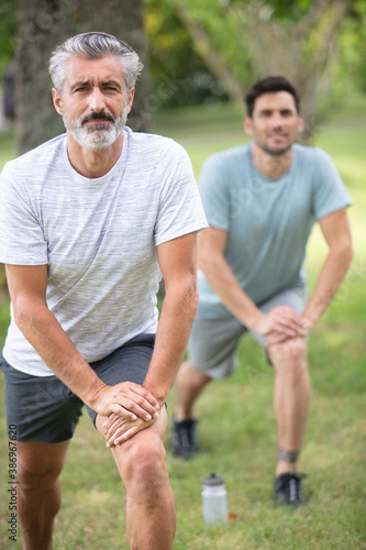 two men exercising stretching their legs