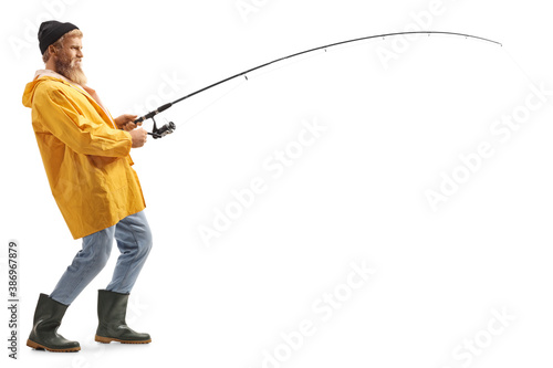 Full length profile shot of a young bearded fisherman catching with a fishing pole