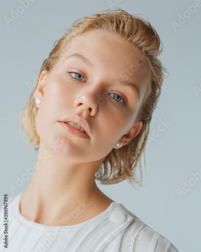 Portrait of model with natural makeup and short hair on white background in studio . Girl with wet styling and natural makeup