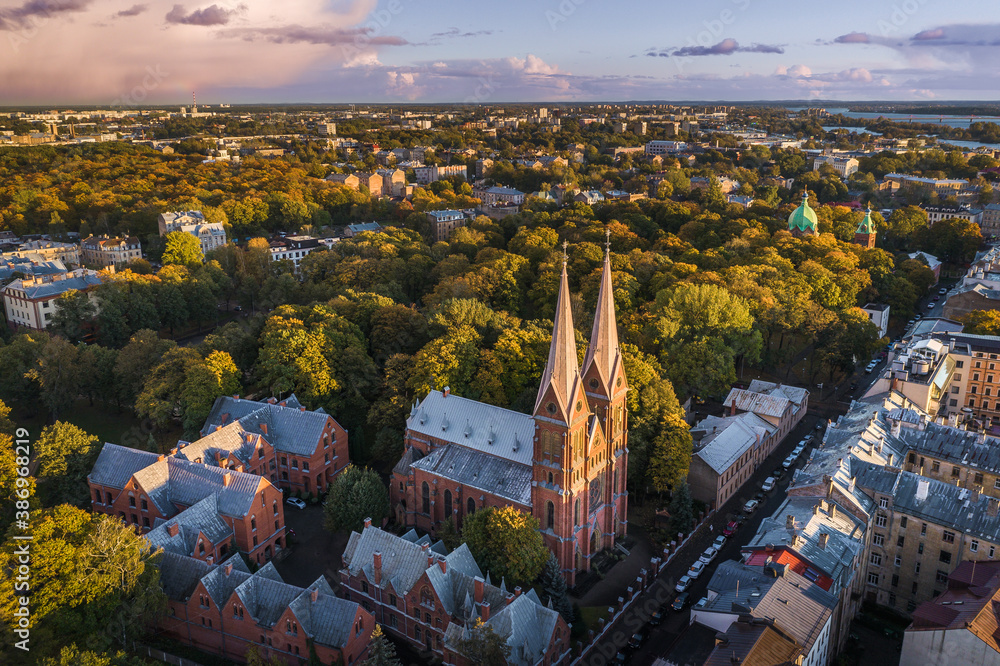 Obraz premium Aerial view of Riga city at colorful sunset. Impressive storm clouds over the city park in autumn colors. 