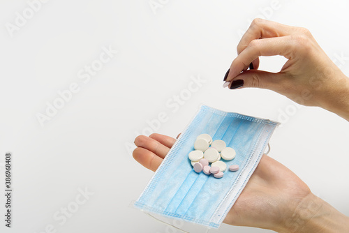 concept covid vaccine pills. COVID-19. Medical mask on a hand with white background. Medicine pills or Vaccine against the virus.