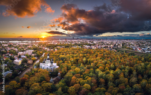 Fototapeta Naklejka Na Ścianę i Meble -  Aerial view of Riga city at colorful sunset. Impressive storm clouds over the city park in autumn colors. 