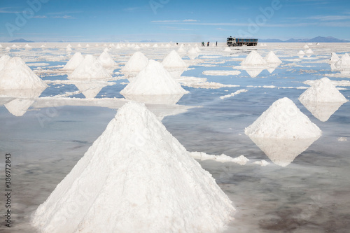 Horizontal view of infinite piles of salt in the Salar de Uyuni­. In the background -far away- workers load salt into a large truck, Bolivia