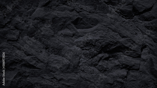 Dark stone background. Black rock texture. Close-up. Stone wall. Volumetric rough basalt granite surface.
