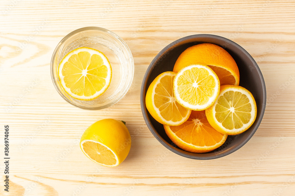 Glass of water and a plate of lemons on a wooden table Glass of water and a plate of lemons on a wooden table