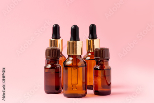 An amber bottle for essential oils and cosmetics stands next to the stone. Glass bottle on a pink background. Dropper  spray bottle. Natural cosmetics concept.