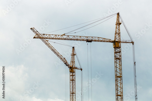 Two yellow construction cranes and blue sky on the background. Industrial landscape. Construction of residential buildings. Business concept.